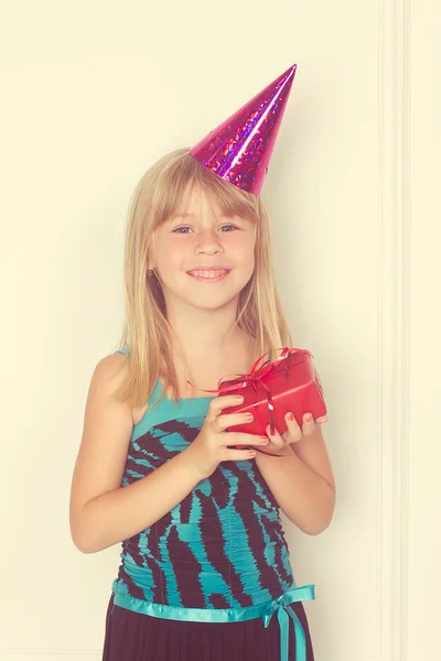 Menina com um presente de aniversário e boné — Fotografia de Stock