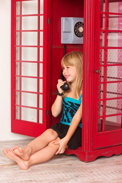 Девушка звонит по красному телефону — стоковое фото