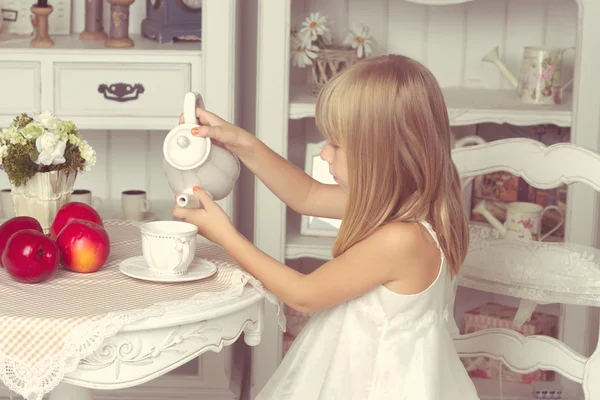 Niña sentada en la mesa con frutas y tetera — Foto de Stock