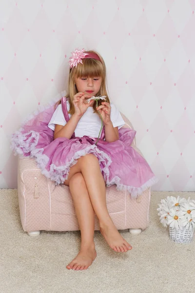 La niña está sentada en una silla. — Foto de Stock