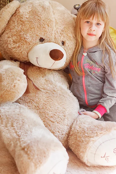 little girl hugging big teddy sitting