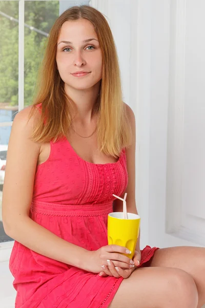 Menina em um vestido rosa com mão de vidro amarelo em casa — Fotografia de Stock