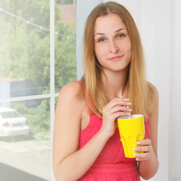 Girl in a pink dress with yellow glass hand at home — Stock Photo, Image