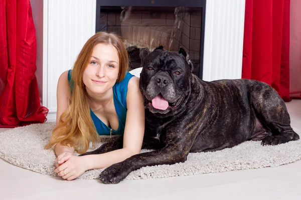 Fille est à la maison à côté de la cheminée avec son chien Cane Corso — Photo