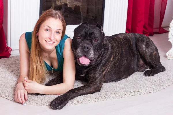 Mujer está en casa junto a la chimenea con su gran perro Cane Corso —  Fotos de Stock