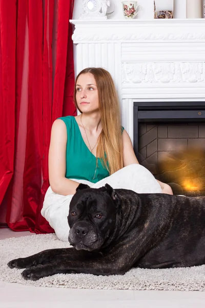 Fille en robe verte assis près de la cheminée avec chien Cane Corso — Photo