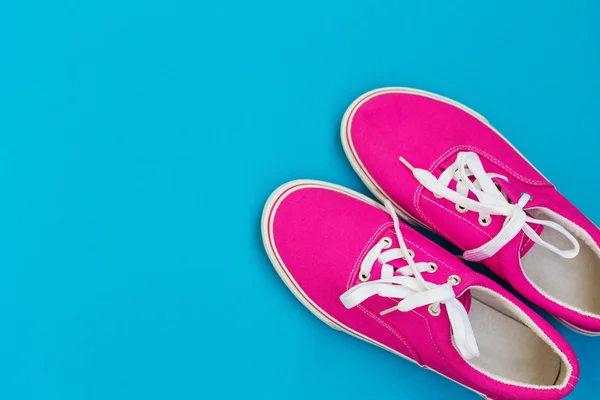 Розовые кроссовки с белыми шнурками на синем — стоковое фото