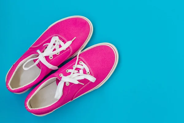 Розовые кроссовки со шнурками на синем — стоковое фото