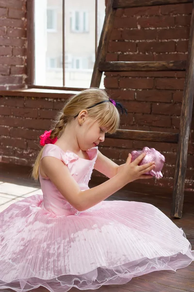 Ragazza 6 anni vestito rosa con salvadanaio tra le mani. Inquadratura verticale — Foto Stock