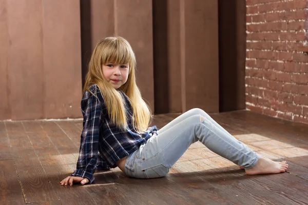 Girl 6 years old in jeans sitting on floor — Stock Photo, Image