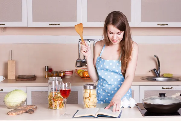 Girl in a blue apron the kitchen — Stock Photo, Image