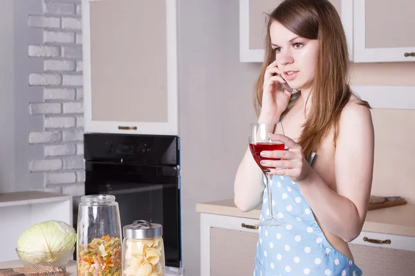 Ragazza in cucina indossando un grembiule sopra il suo corpo nudo con un bicchiere di vino rosso — Foto Stock