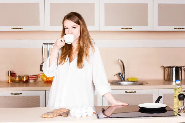 Girla weißes Männerhemd mit langen wallenden Haaren trinkt Tee in der Küche — Stockfoto