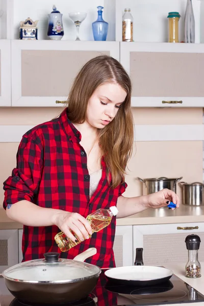 Chica con el pelo largo y fluido en camisa roja macho prepara la cocina. Vertical —  Fotos de Stock