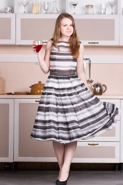 Jolie robe jeune femme tenant un verre de vin dans sa cuisine . — Photo