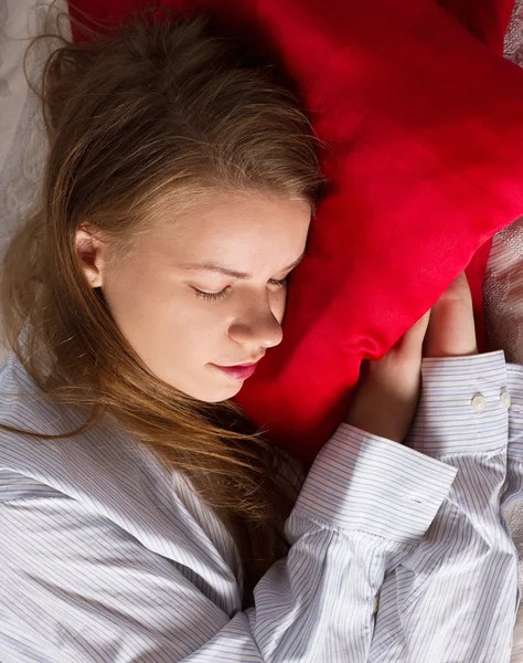 Hermosa mujer está durmiendo en la almohada roja — Foto de Stock