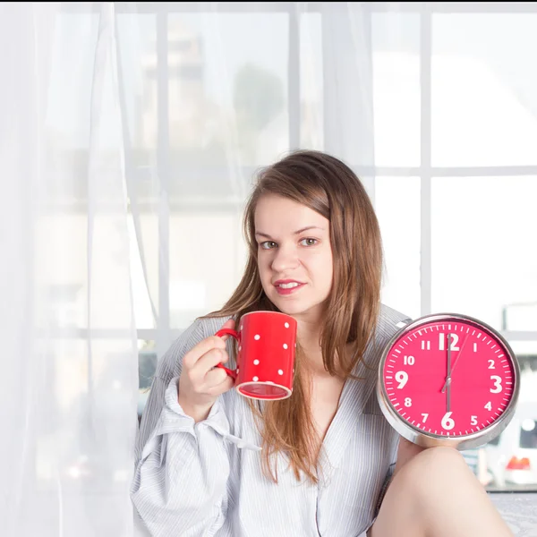 Glückliches Mädchen wacht morgens um 6 Uhr mit Wecker und Kaffeetasse auf — Stockfoto