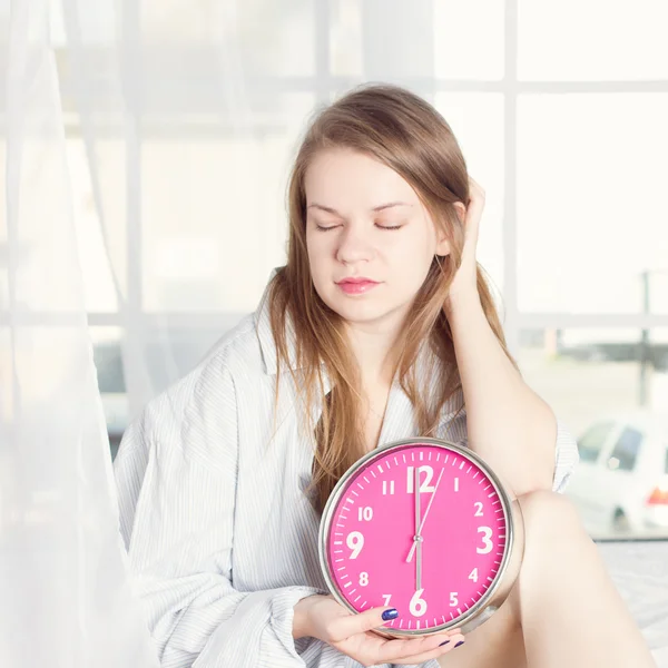 Mladá žena s alarmclock na posteli na ráno — Stock fotografie