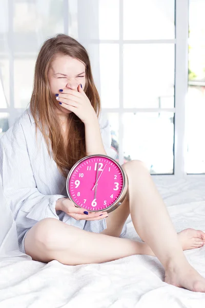 Mladá žena s alarmclock na posteli na ráno — Stock fotografie