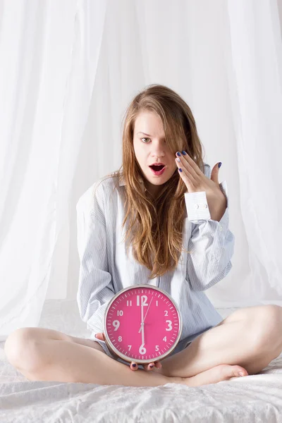 Girl with big pink clock the morning in bed — Stock Photo, Image