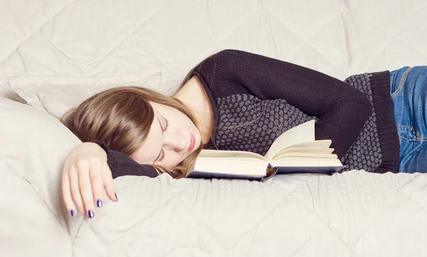 Menina bonito dormindo enquanto segurando um livro deitado — Fotografia de Stock