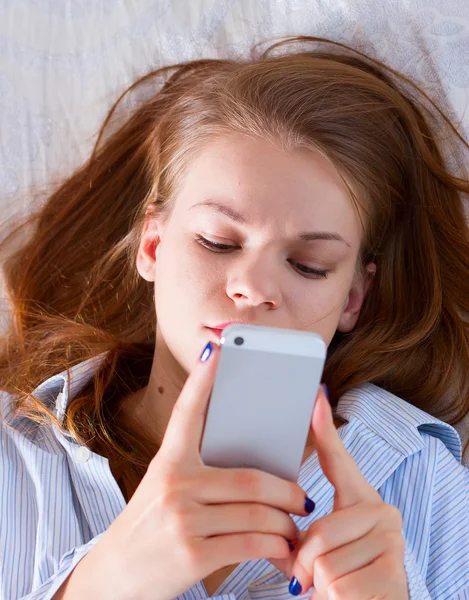 Žena odesílání textu s mobilním telefonem v posteli — Stock fotografie