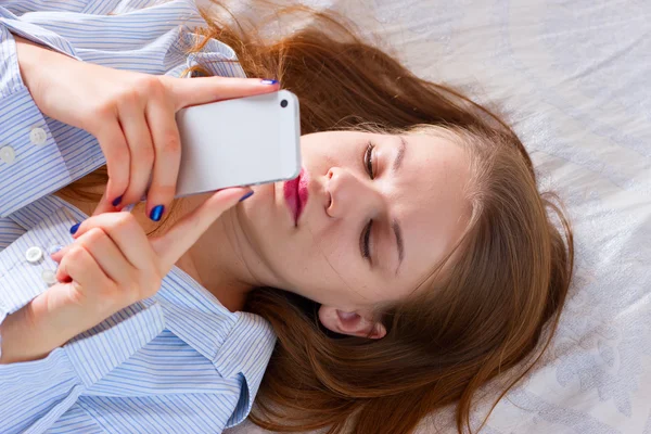 Kadın yatakta bir cep telefonu ile metin gönderme — Stok fotoğraf