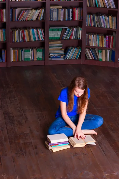 Menina senta-se no chão na biblioteca — Fotografia de Stock