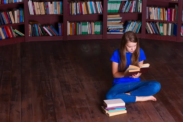 Meisje zit op de vloer in de bibliotheek — Stockfoto