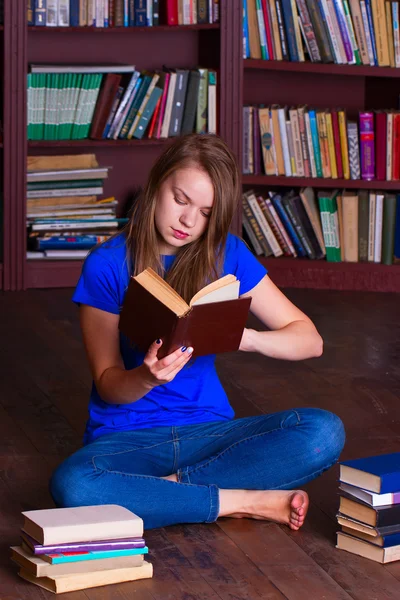 Dívka sedí na podlaze v knihovně — Stock fotografie