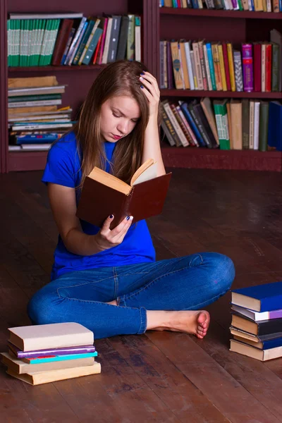 Meisje zit op de vloer in de bibliotheek — Stockfoto