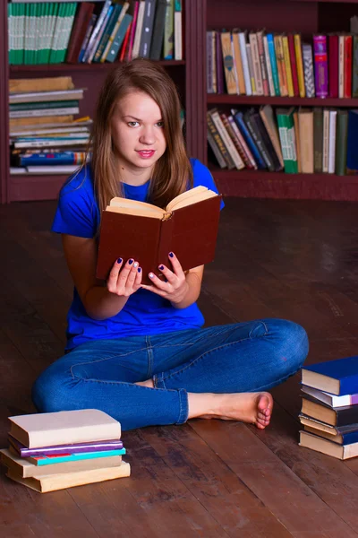 Dziewczyna siedzi na podłodze w bibliotece — Zdjęcie stockowe