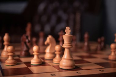 Oyun tahtasındaki tahta satranç kralı. Oyunun sıcak atmosferi. Çerçevenin ortasında..