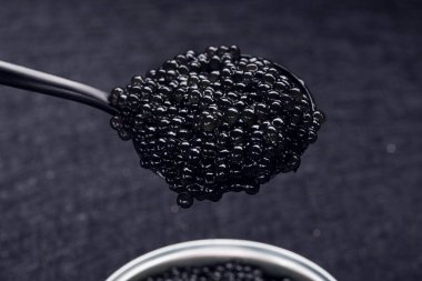 Koyu arkaplanda siyah havyarlı bir kaşık. Deniz ürünleri diyeti. zengin yiyecekler.