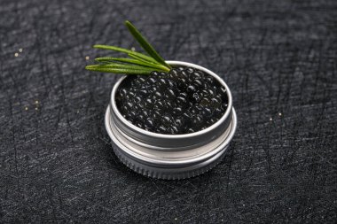 Taş zemin üzerinde biberiye dalı olan siyah balık havyarı. Deniz ürünleri diyeti.