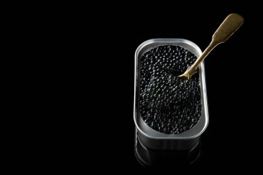 Siyah arka planda izole edilmiş metal tavada pahalı siyah mersin balığı havyarı.