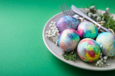 Plakalı Paskalya minimalizmi yemek kavramı ve yeşil arka planda boyanmış yumurtalar. 