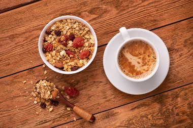 Tahta bir masada kurumuş meyveli granola ile kahve fincanı. Sağlıklı kahvaltı konsepti. Üst görünüm.