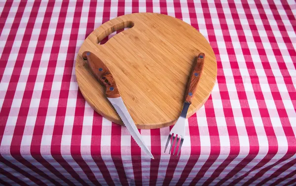 Cutting board on tablecloth — Stock Photo, Image