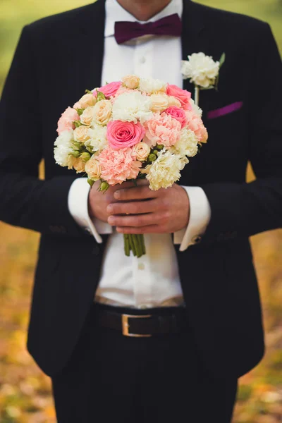 Groom holding wedding flowers — Stock Photo, Image