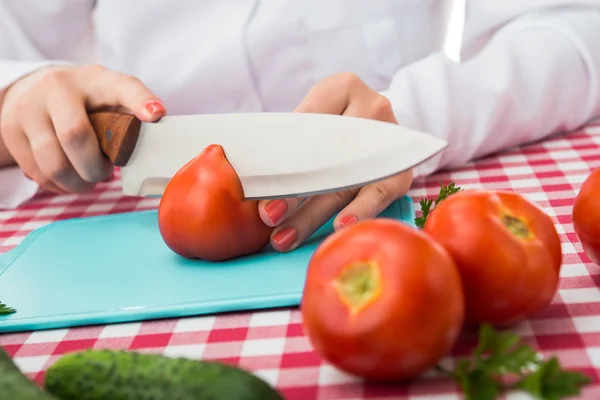 Female cook cuts tomato — Stock Photo, Image