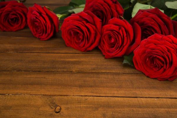 Κόκκινα τριαντάφυλλα σε ξύλινο τραπέζι — Φωτογραφία Αρχείου
