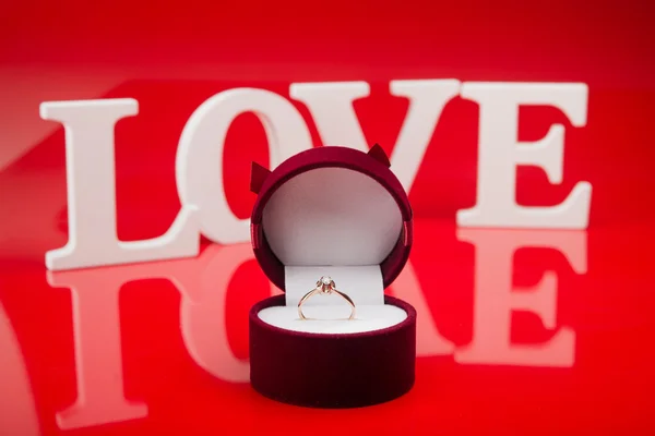 Золотое кольцо в коробке на красном фоне — стоковое фото