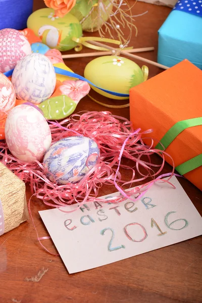 Easter with eggs in nest and yellow tulips over blue wooden table. Top view — Stock Photo, Image