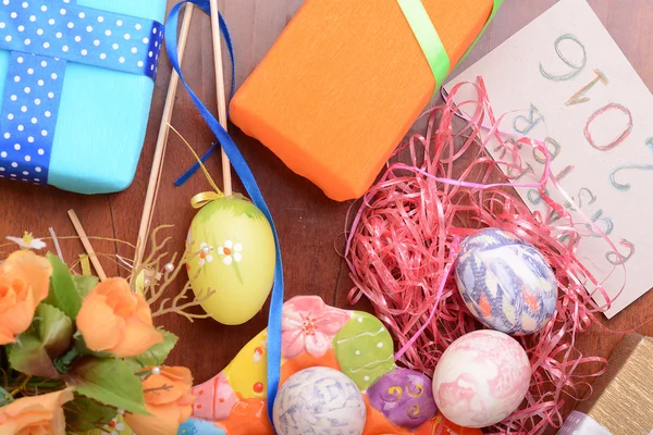 Easter with eggs in nest and yellow tulips over blue wooden table. Top view — Stock Photo, Image