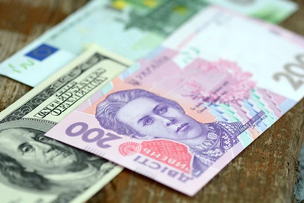 Dollar euro en hryvnia bankbiljetten op houten achtergrond — Stockfoto