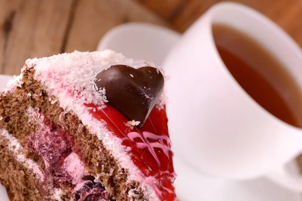 Pedaço de bolo com coração de chocolate em fundo de madeira — Fotografia de Stock