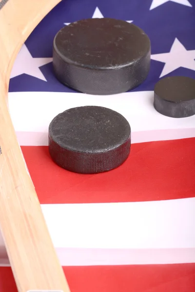 Hockeyausrüstung mit Stock und Puck auf einer amerikanischen Flagge, um auf eine patriotische amerikanische Sportart zu schließen. — Stockfoto