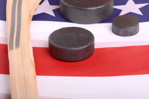 Hockeyausrüstung mit Stock und Puck auf einer amerikanischen Flagge, um auf eine patriotische amerikanische Sportart zu schließen. — Stockfoto