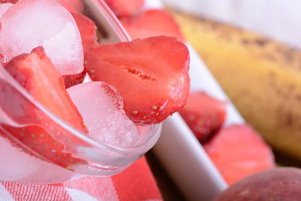 Uma fatia de morango vermelho em prato de vidro com bananas e pêssego, conceito de comida saudável — Fotografia de Stock